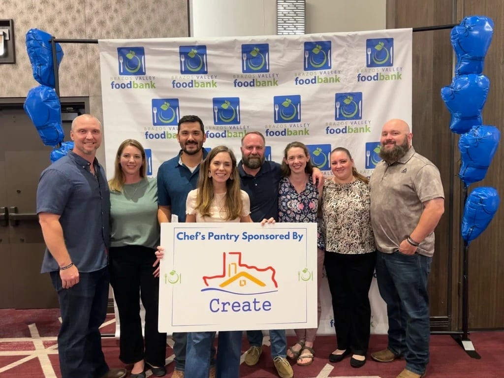 Create representatives gathered at a Brazos Valley Food Bank event with a Create sponsorship sign