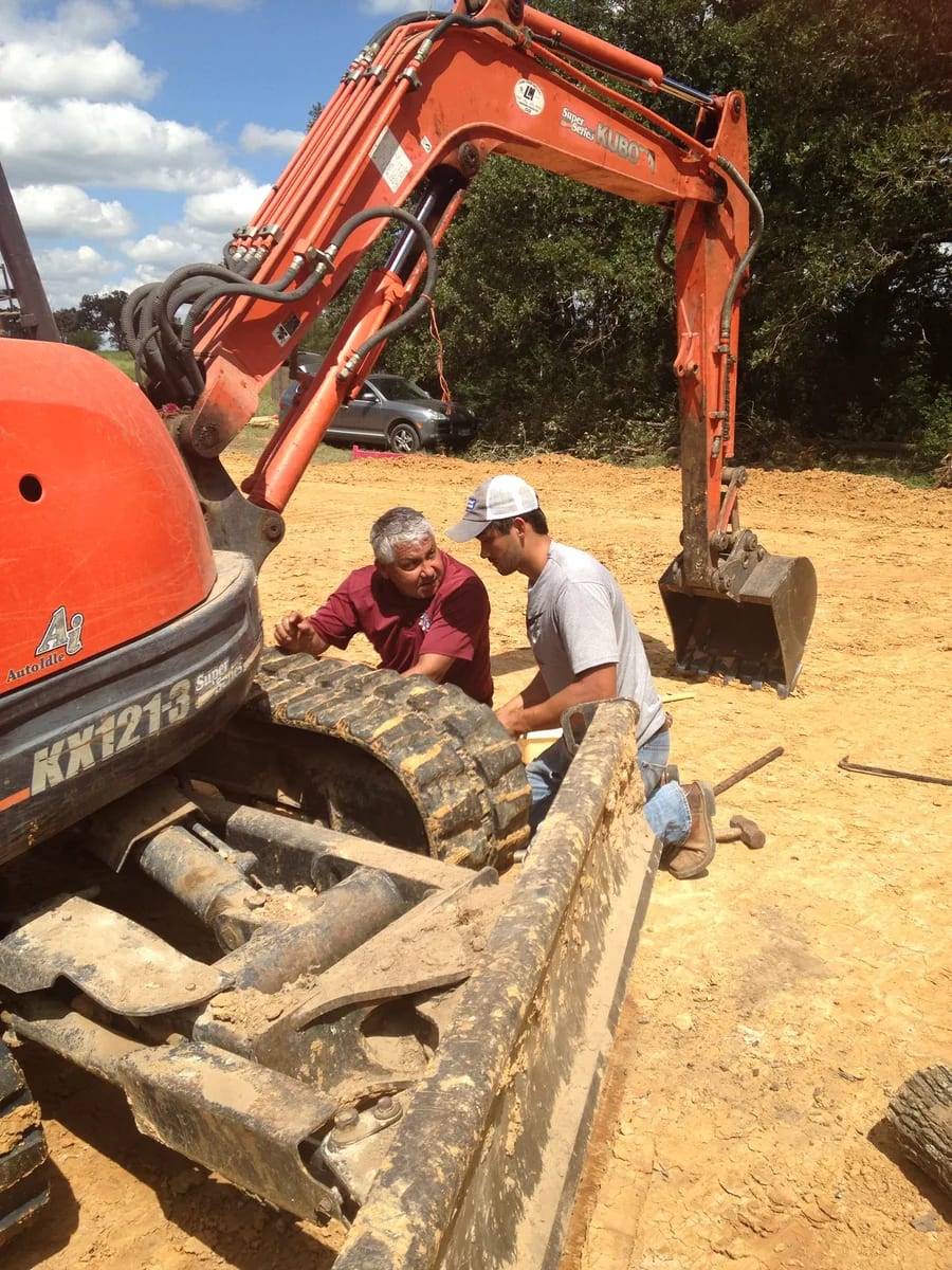 Team members working beside construction equipment